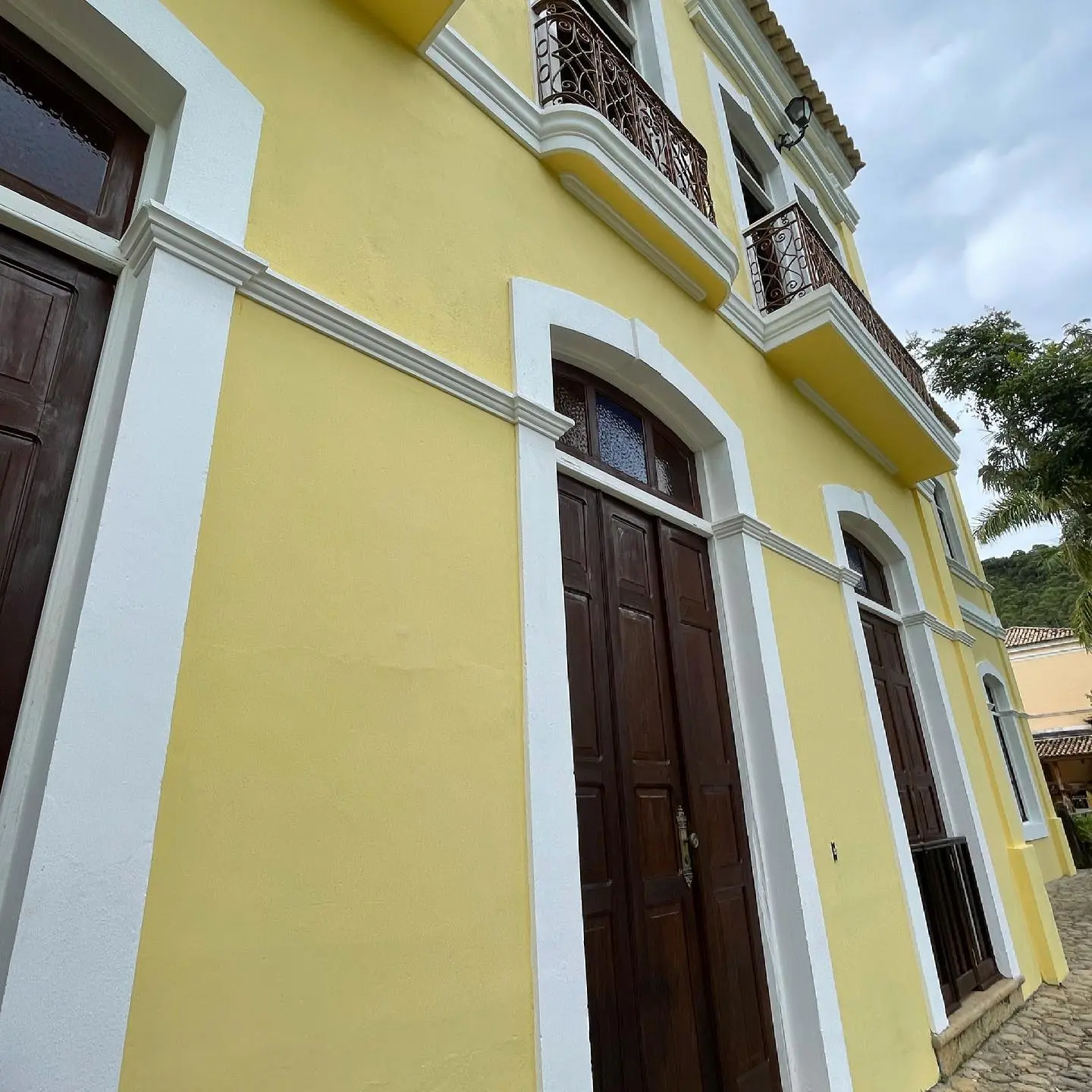 Fachada amarela do casarão da Fazenda Neuchatel com arcos e sacadas de ferro forjado